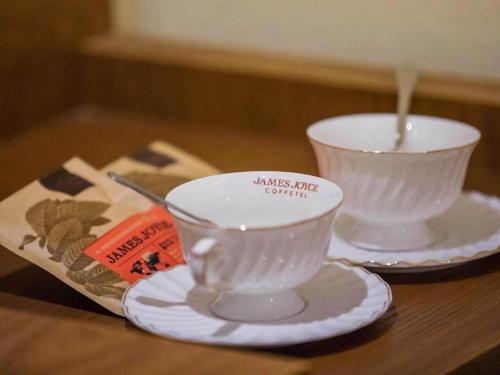 two white cups and plates on a wooden table at James Joyce Coffetel Qufu Tourist Center Gulou Street Sankong Scenic Spot in Jining