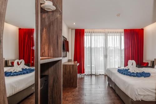 a hotel room with two beds with red curtains at C202 Sun and Fun Kids Club 1BR 500m to Beach in Kata Beach