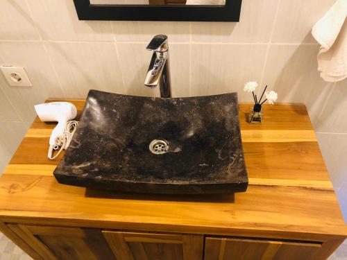 un fregadero negro sentado en la parte superior de un mostrador de madera en Villa Shiva - Lotus, en Uluwatu