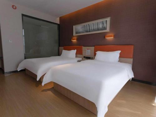 two beds in a hotel room with white sheets at 7Days Premium Yichang Railway Station East in Yichang
