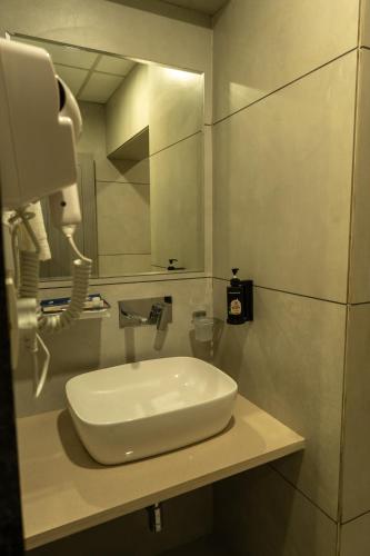 a white sink in a bathroom with a phone at Hotel City Pride in Mahuva