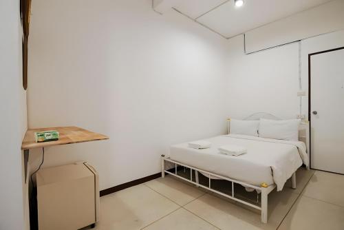 a white bedroom with a bed and a table at XX GO INN Asiatique Bangkok - โกอินน์ เอเชียทีค เจริญกรุง in Bangkok