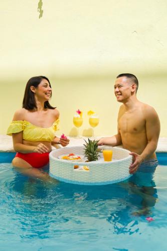 a man and a woman sitting in the water with cocktails at Casa Bien Estar - Centro Merida in Mérida