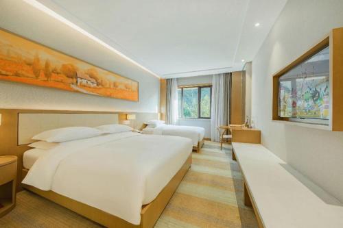 a hotel room with two beds and a painting on the wall at Deefly Yinrun Town Hotel in Deqing