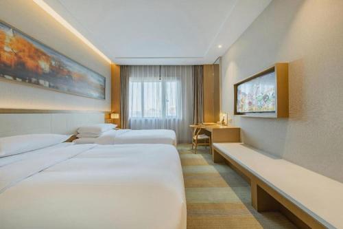 a hotel room with three beds and a desk at Deefly Yinrun Town Hotel in Deqing