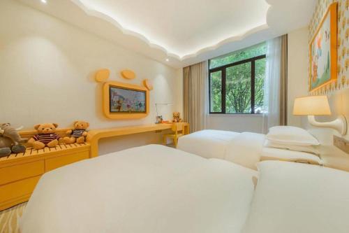 a bedroom with two white beds and a window at Deefly Yinrun Town Hotel in Deqing