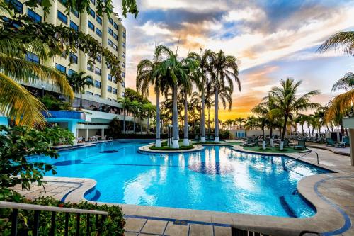 a large swimming pool with palm trees in front of a building at Hotel Olé Caribe in Macuto