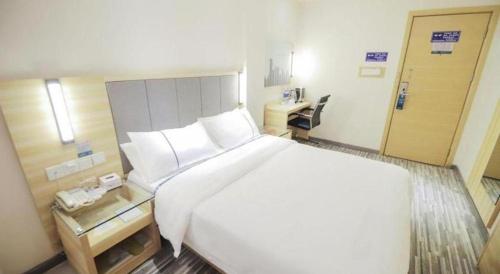 a bedroom with a large white bed and a desk at City Comfort Inn Changsha Window of the World Zhongmao City in Changsha