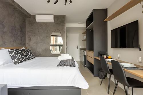 a bedroom with a white bed and a desk with a dining room at Nik Perdizes in Sao Paulo