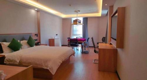 a bedroom with a bed and a desk and a mirror at GreenTree Inn Express Zhangjiagang Hexing Town Shazhou Professional Institue of Technology in Qiwei