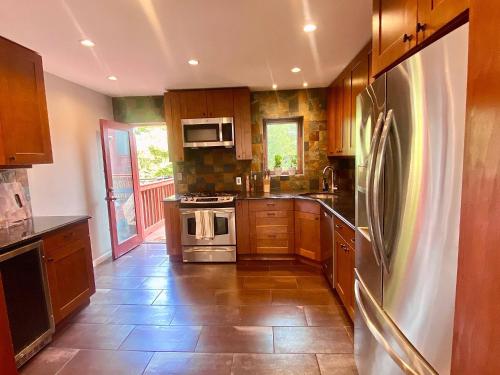 a kitchen with wooden cabinets and stainless steel appliances at Easy PATH&Bus access- NYC| designer home + Deck. in Jersey City
