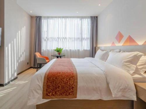 a bedroom with a large bed and a table at Borrman Hotel Hefei Yaohai Wanda Linquan East Road in Hefei