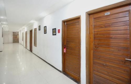 a hallway with wooden doors in a building at Super Hotel O Queensland in Amritsar