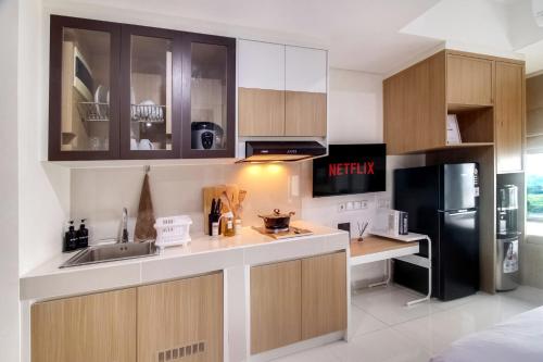 a kitchen with wooden cabinets and a black refrigerator at 1BR Chadstone With Pool and Gym in Kedungg
