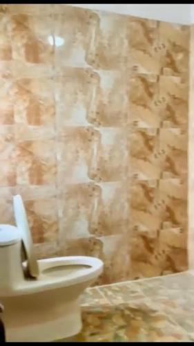 a bathroom with a toilet and a stone wall at MADAME Flexstay Girls Hostel in Kathmandu