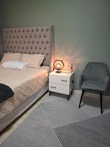 a bedroom with a bed and a chair and a nightstand at Cosy Cottage 1 in Francistown