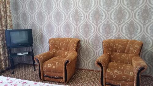 two chairs and a television in a room at Apartment Airkassa in Khujand