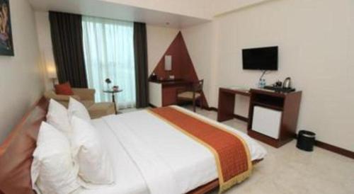 a bedroom with a bed and a desk and a television at Grand Surya Hotel Kediri in Kediri