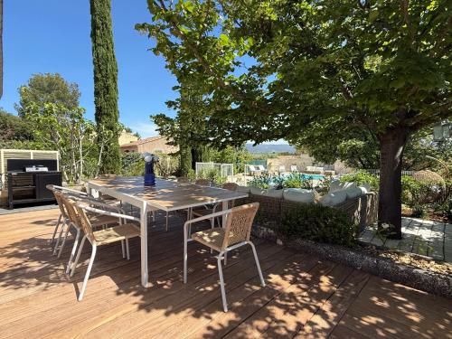 une table et des chaises sur une terrasse avec un arbre dans l'établissement La Note Bleue Luberon, à Maubec