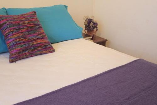 a bed with a colorful pillow on top of it at Casa Suyay in Tilcara