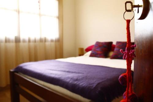 a bedroom with a bed with purple sheets and a window at Casa Suyay in Tilcara