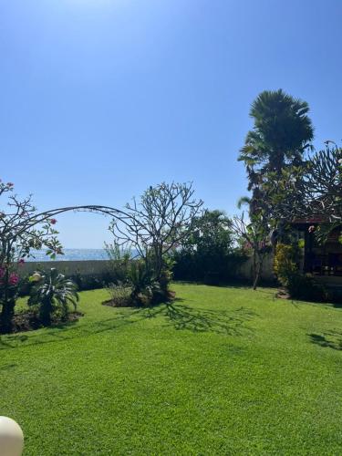 a field of green grass with trees and a house at Beachfront Villa Jepun Segara in Banjar