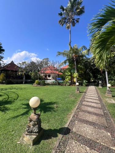 a walkway in a park with palm trees and a house at Beachfront Villa Jepun Segara in Banjar