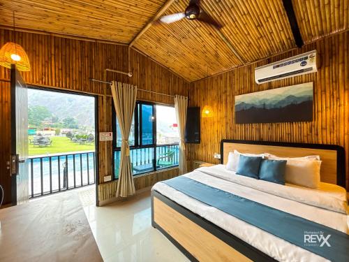 a bedroom with a bed and a large window at Euphoric Tiger Resort in Rishīkesh