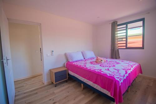 a bedroom with a pink bed with a stuffed animal on it at Bora Bora House Maha in Bora Bora