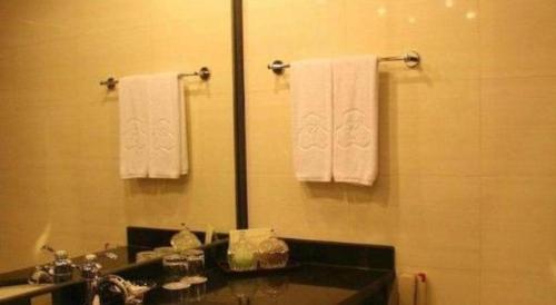 a bathroom with a sink and a mirror and towels at Capital Hotel in Beijing