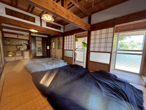a large bed in a room with windows at -大人数で泊まれる一棟貸し-なかまあじーんやー海近くの素敵な島暮らし体験-手久津久- in Kikaijima