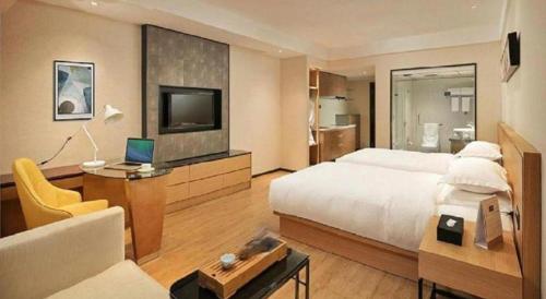 a bedroom with a bed and a television and a couch at Kingtown Hotel Hongqiao Shanghai in Shanghai