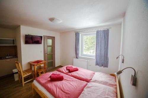 - une chambre avec un lit doté de draps rouges et une fenêtre dans l'établissement Apartments Kvasničník, à Demänovská Dolina