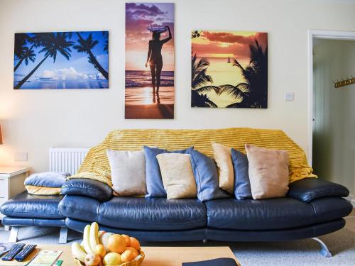 a living room with a blue couch with four pictures on the wall at Between The Forest And The Sea in New Milton