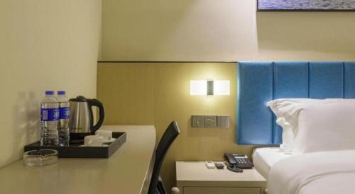 a hotel room with a bed and a desk with a phone at Jingtu hotel zhanjiang dingsheng plaza store in Zhanjiang