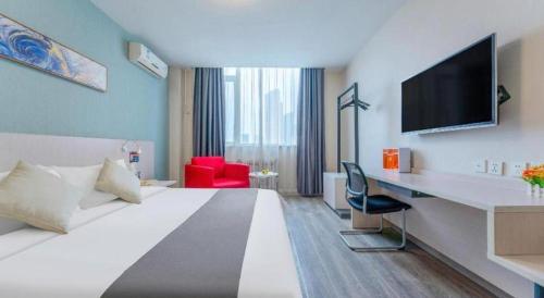 a hotel room with a bed and a desk with a television at Zhangye Pinmu Hotel(Yuncheng Zhongyin Avenue Store) in Yuncheng