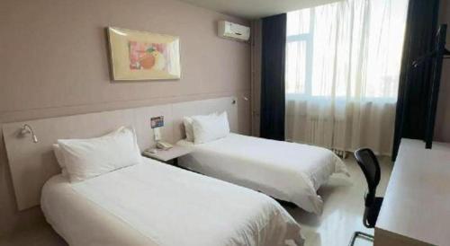 a hotel room with two beds and a window at Zhangye Pinmu Hotel(Yuncheng Zhongyin Avenue Store) in Yuncheng