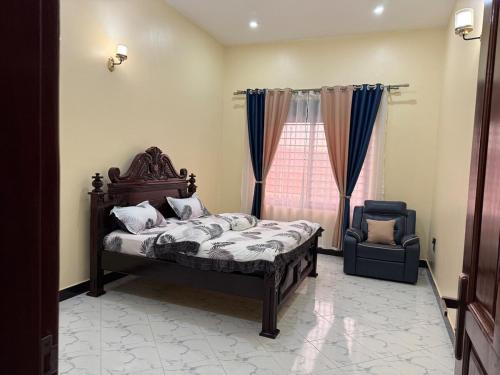 a bedroom with a bed and a chair and a window at Uptown retreat home Su casa Najjera 1 in Buwate