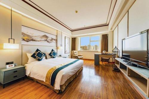 a bedroom with a large bed and a flat screen tv at Junyu Grand Hotel Qinhuangdao in Qinhuangdao