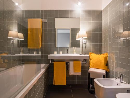 a bathroom with a tub and a sink and yellow towels at Cardosas Boutique Apartment in Porto