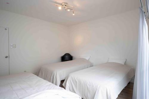 two beds in a room with white walls at Beach & Stay 鎌倉長谷 暮らすように泊まる 長谷駅すぐ 海近の個室ゲストハウス in Kamakura