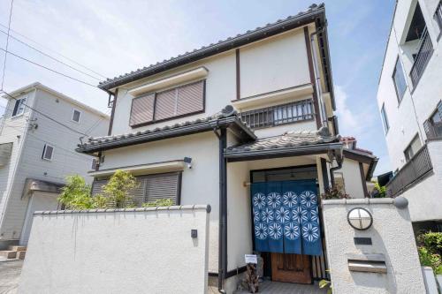 a white house with a blue door at Beach & Stay 鎌倉長谷 暮らすように泊まる 長谷駅すぐ 海近の個室ゲストハウス in Kamakura
