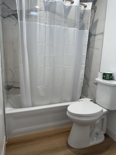 a white bathroom with a toilet and a shower at Sun Leisure Motel in Menifee