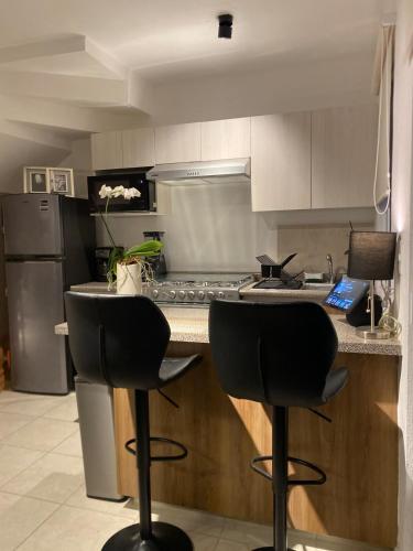 a kitchen with two black bar stools and a counter at Departamento en Boca del Rio Ver in Boca del Río