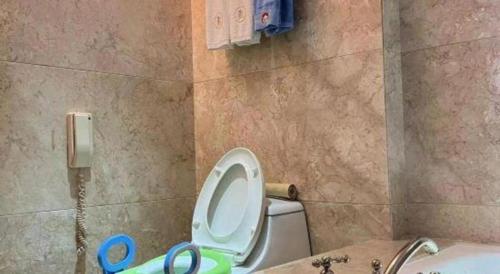 a bathroom with a toilet and a phone on the wall at King Century Hotel in Zhongshan