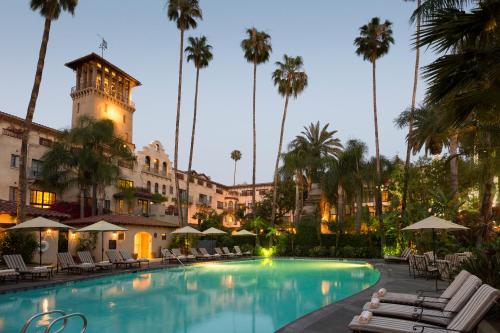 a hotel pool with chairs and palm trees at dusk at The Mission Inn Hotel and Spa in Riverside