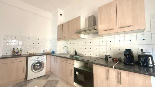 - une cuisine avec des placards en bois et un lave-linge dans l'établissement La Baieta - Typical Nice Apartment, à Nice