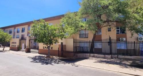 a building with a fence and a tree in front of it at JEFFERSON'Self-Catering in Windhoek