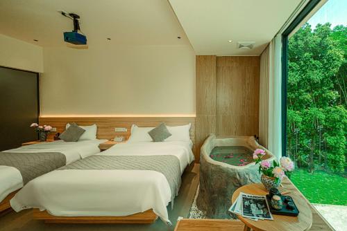 a hotel room with three beds and a window at Panda's Home Private Hot Spring Cinema Hotel in Taiping