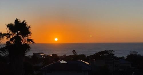 a sunset over the ocean with a palm tree at Guest Suite in Marino in Marino